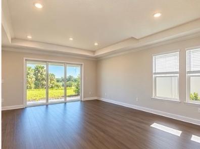 Open great room with wood-look floors and sliding glass doors to the lanai