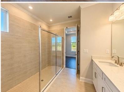 Primary bathroom with large glass-enclosed tile shower and dual vanity